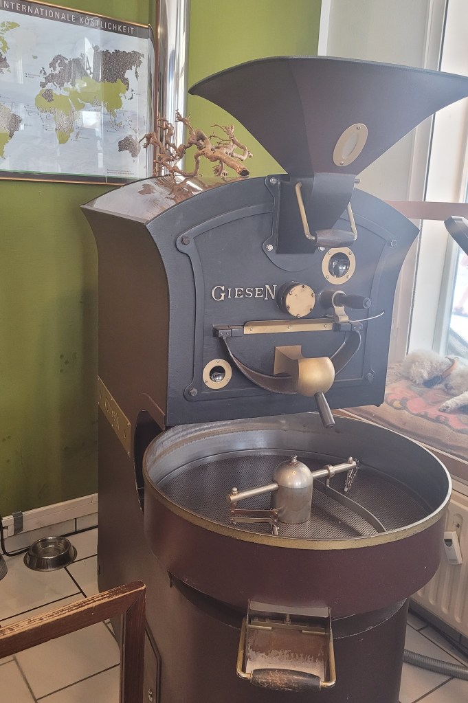 Ein Röster der Marke Gießen für Chargen von 2kg Kaffee vor einer grünen Wand mit einer Weltkarte