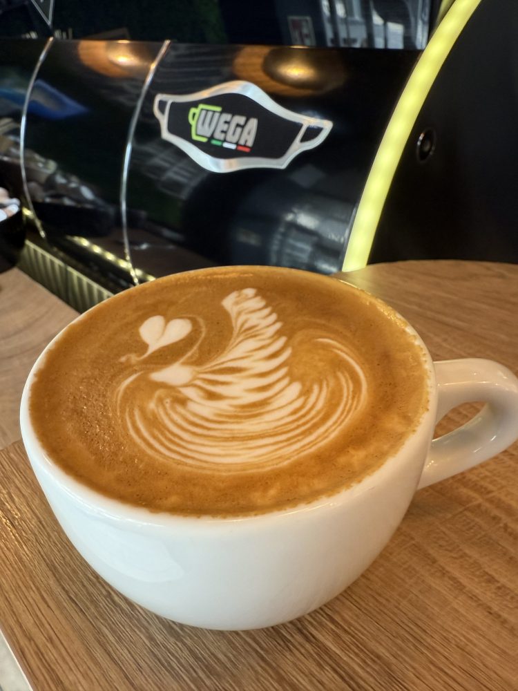 Das Bild zeigt eine Tasse Cappuccino mit perfekter Latte Art. Das Motiv ist ein mehrfach gefächerter Schwan mit einem kleinem Herz als Kopf.